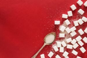 Sugar and a spoon on red background